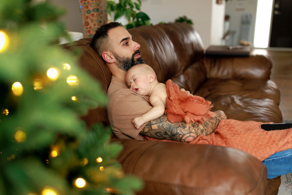 dad holding sleeping baby on couch