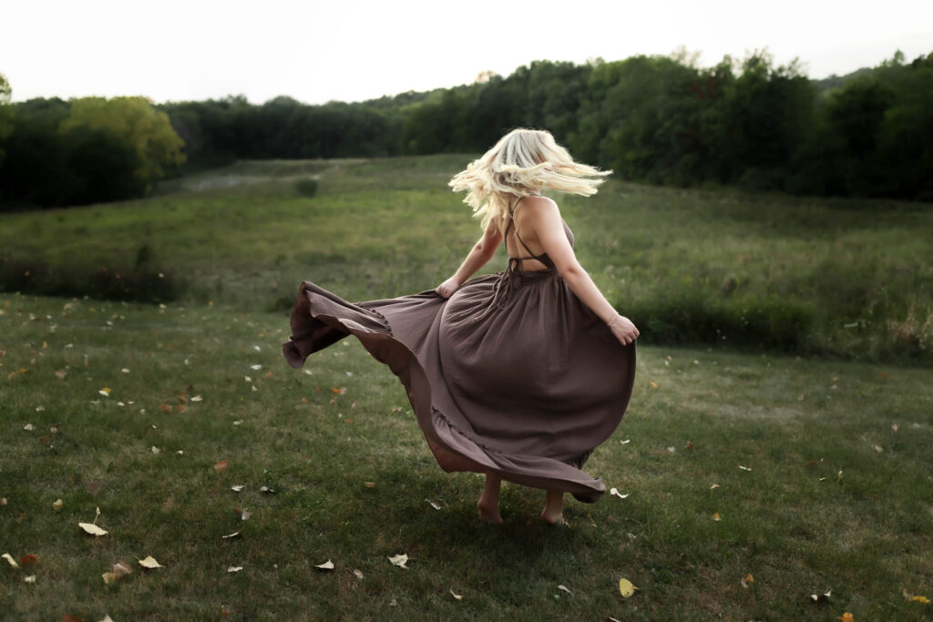 woman twirling in brown dress in large open field