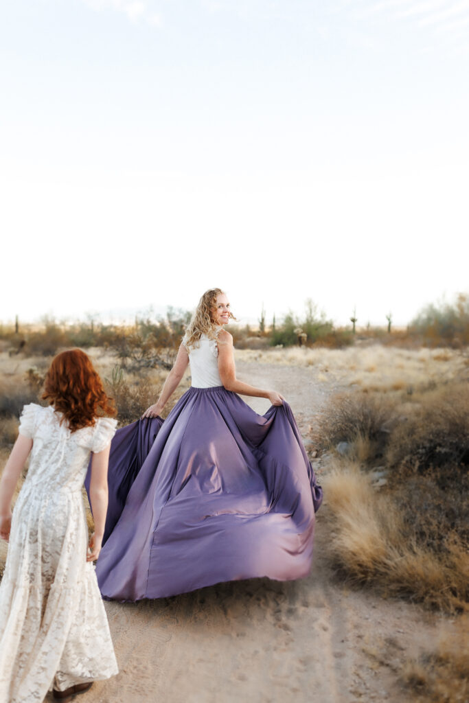 red head woman in purple skirt running through the desert