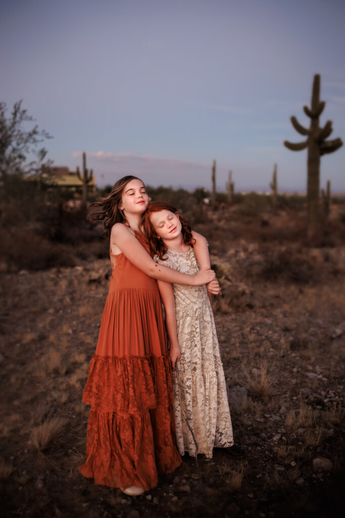 lifestyle photography in arizona desert with two girls embracing with eyes closed