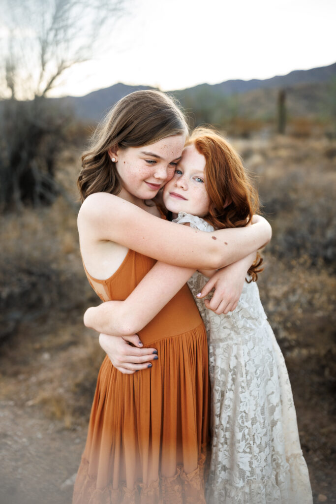 sisters embracing in a hug in the arizona desert for lifestyle photos