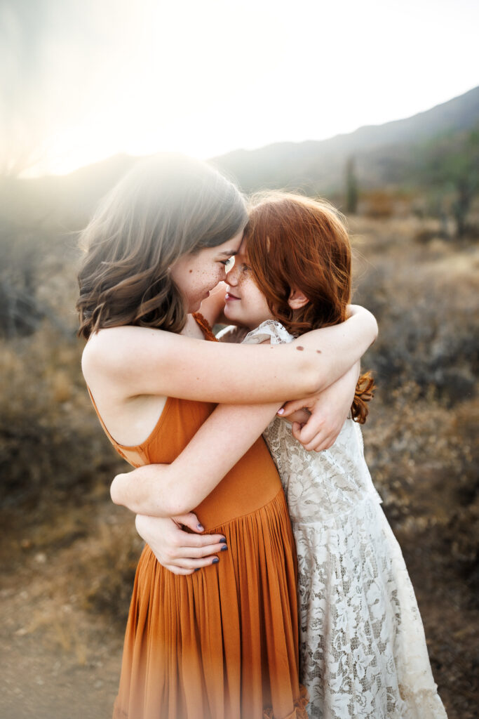 two sisters hugging forehead to forehead with arms wrapped around each other in a hug