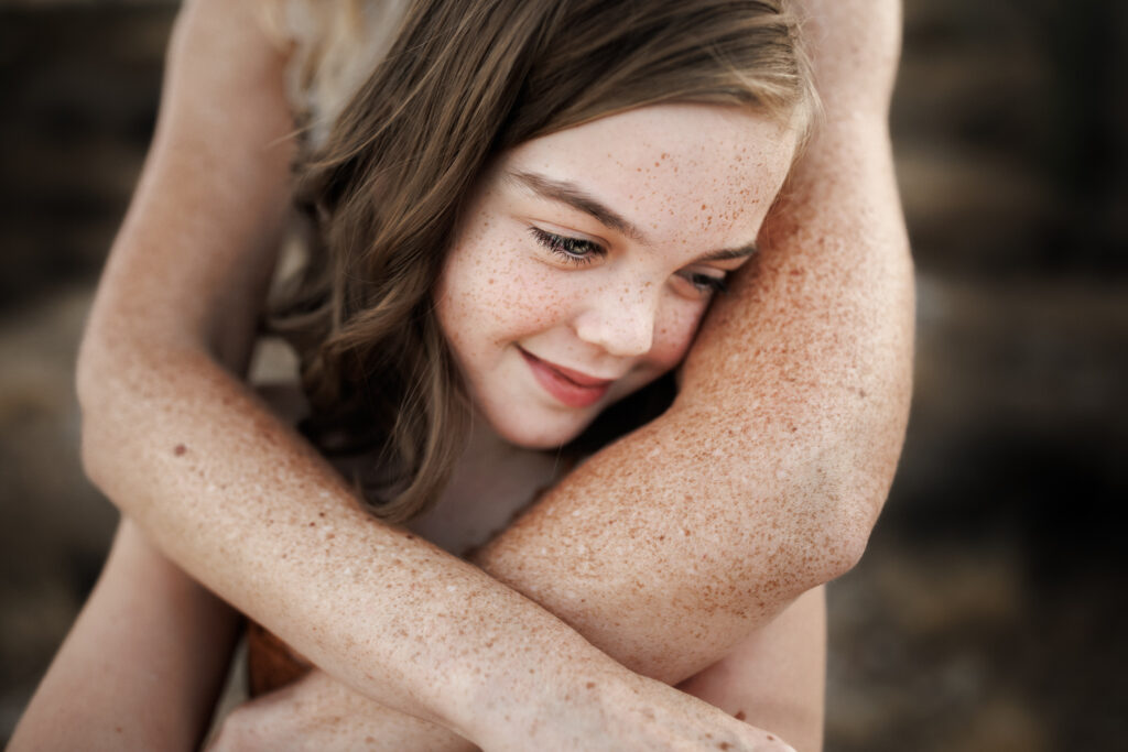 lots of freckles on little girl with moms arms wrapped around during lifestyle photoshoot