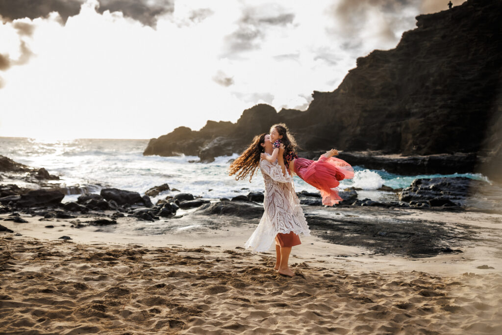 mother spinning daughter on hawaii beach from behind the scenes of a photoshoot