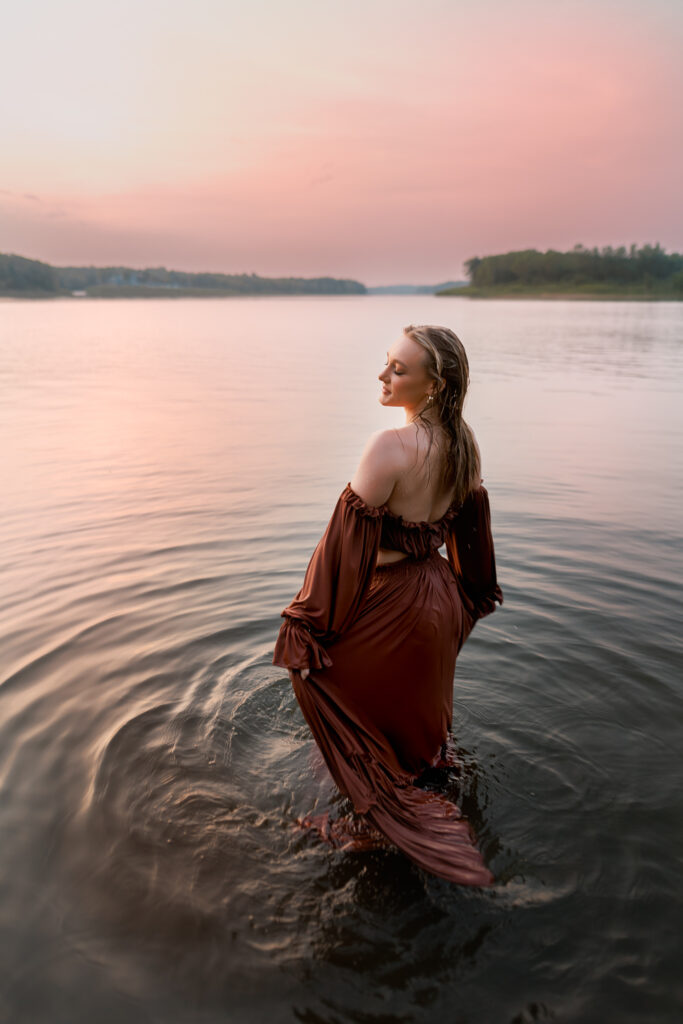 senior photos in the water with girl in two piece gown fully wet and eyes closed