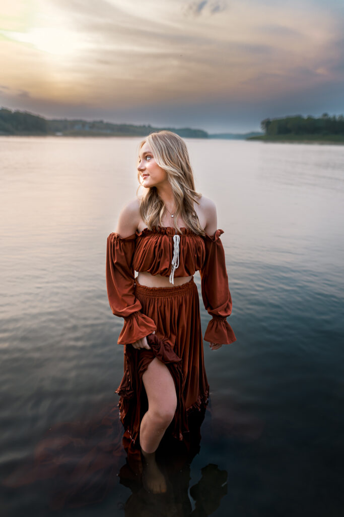 senior pictures in the water with girl modeling two piece zebubeyou gown in deep rust red