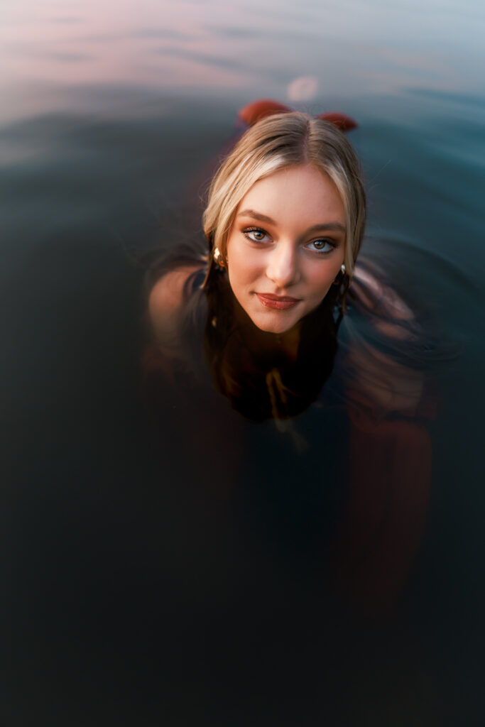 senior portrait in the water with close up of girl looking directly into the camera