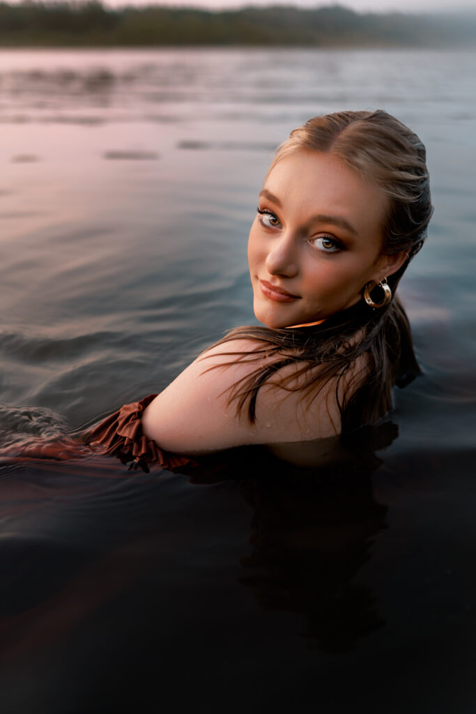 senior portrait in the water with girl nearly fully submerged