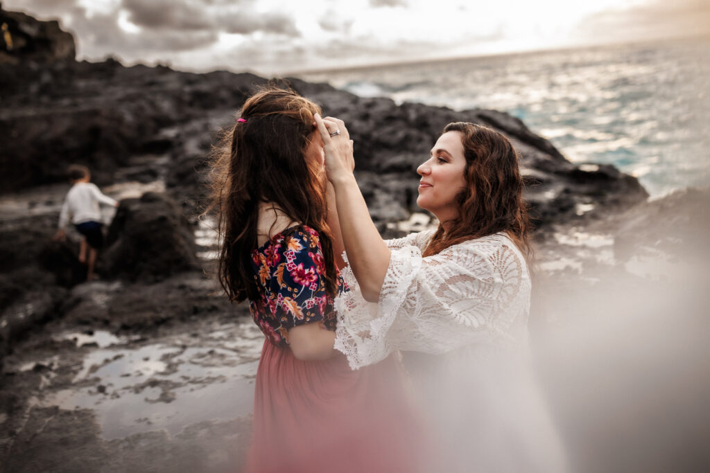 tender moment between mom and daughter as mom pushes hair out of daughters face