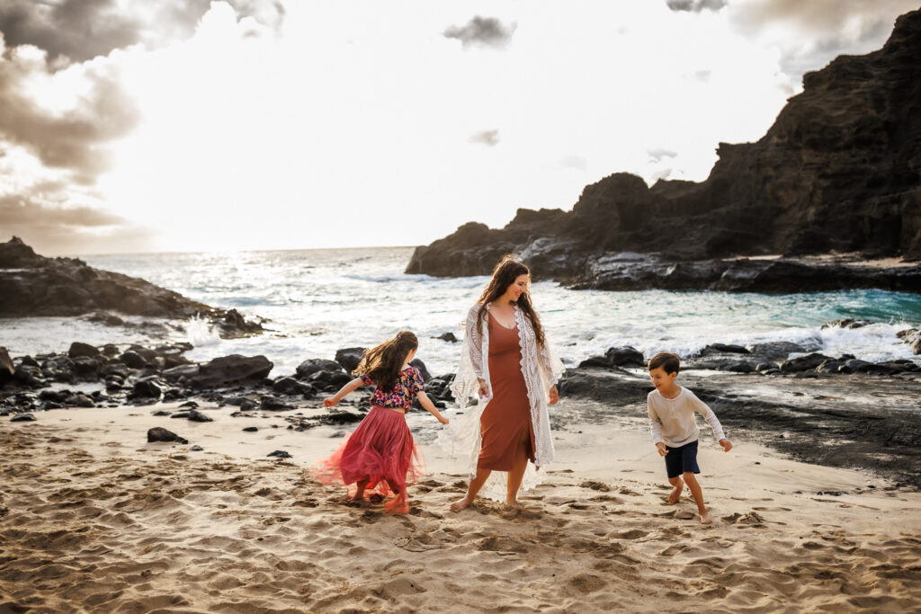 children chasing each other as they run around mom during photoshoot on the beach