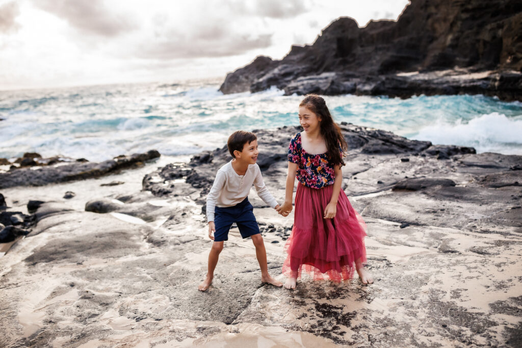 children playing while holding hands during beach photoshoot in hawaii