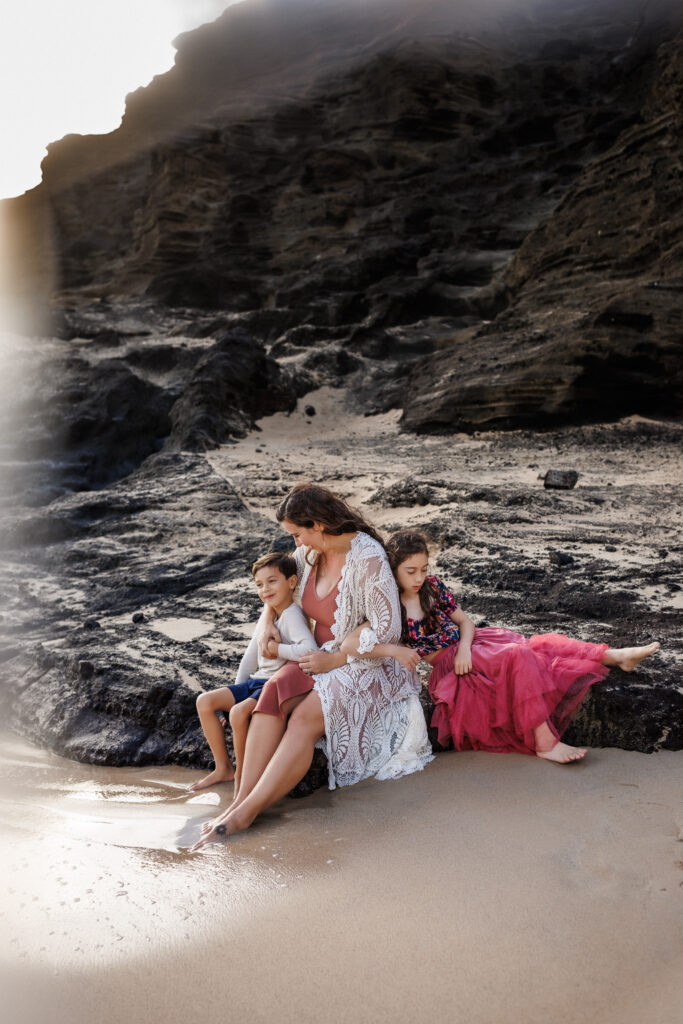 calm family photo sitting on the rocks of the beach