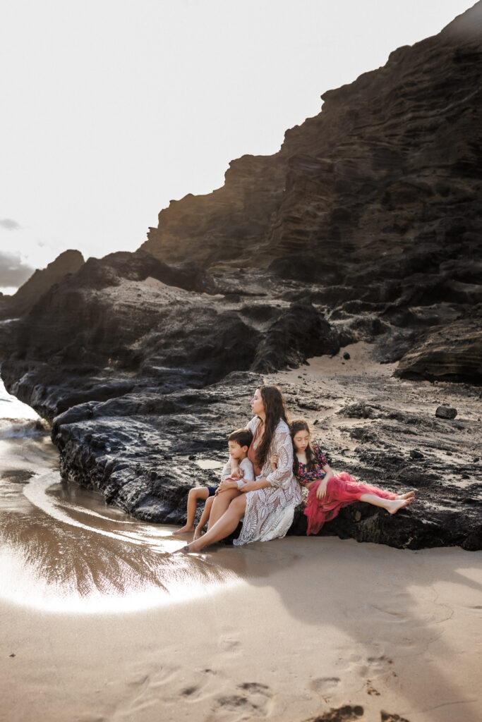 behind the scenes image of family quietly sitting on the rocks of the beach