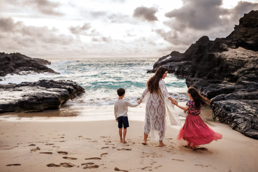 view of family's back as they play on the beach during family photoshoot