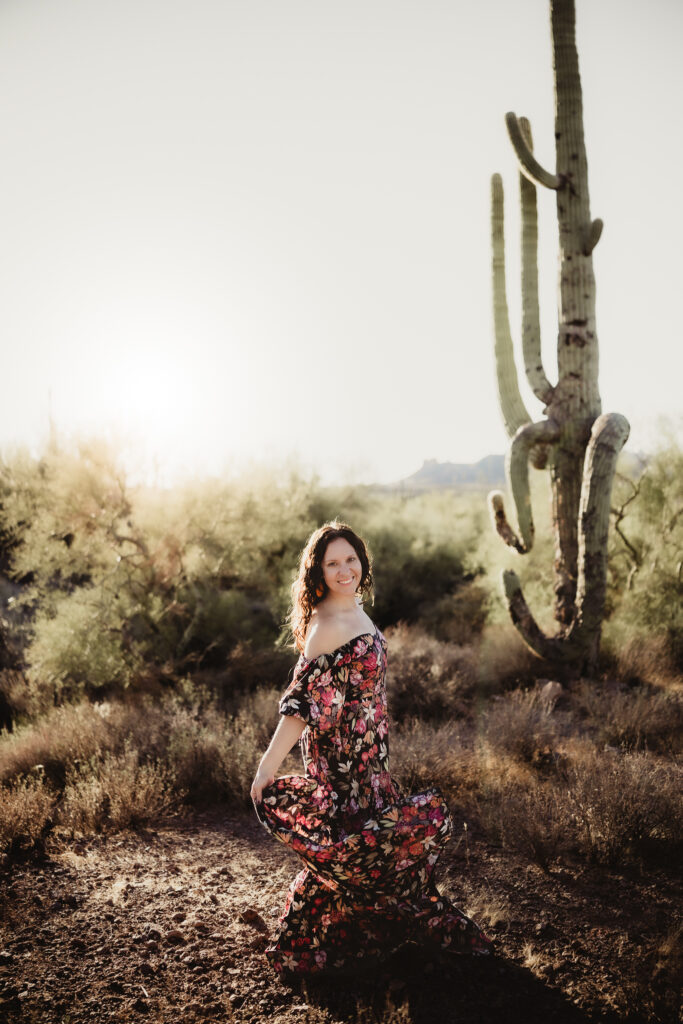 curly hair woman in floral gown twirling in the desert for photos